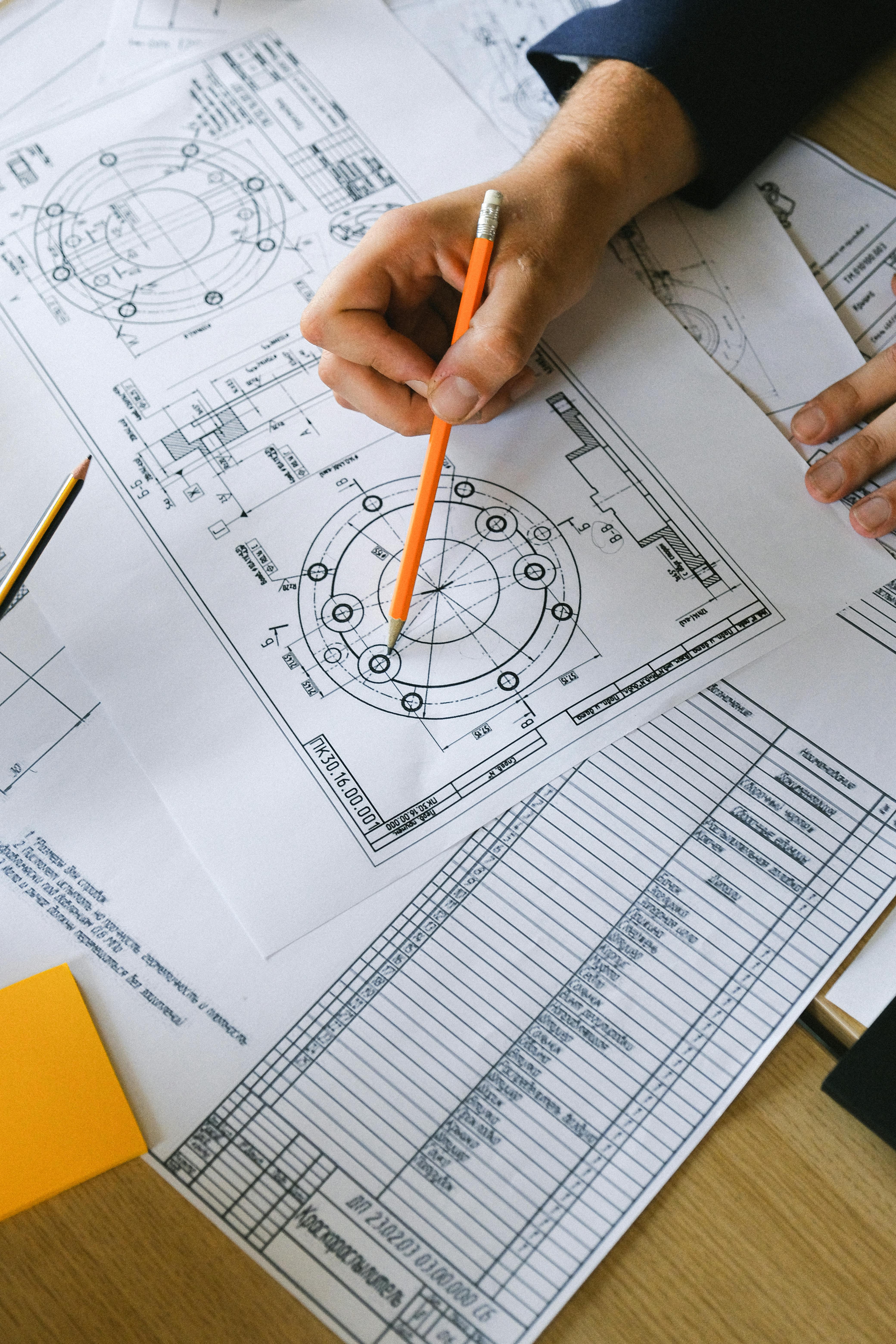 Engineering drawing with person holding a pencil